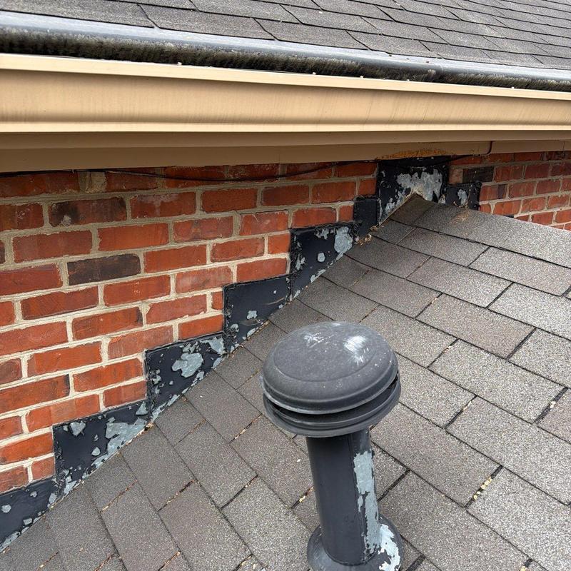 Roof vent and shingle damage near brick flashing