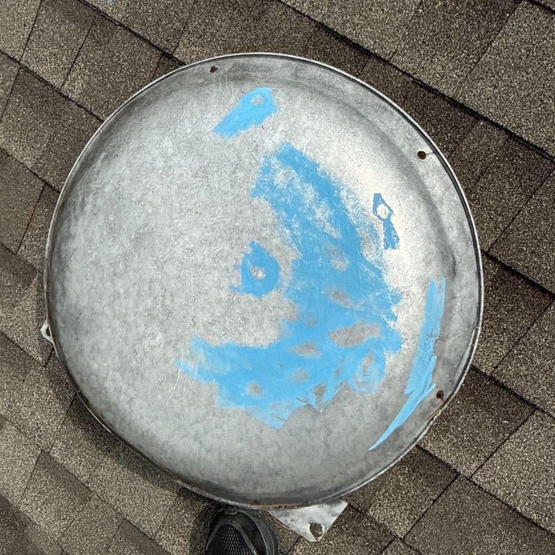 Metal roof vent cap with worn paint on shingles