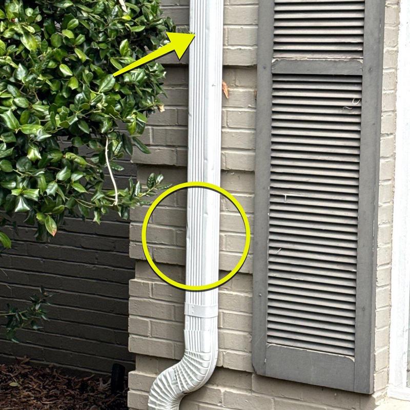 Downspout with dent and paint damage on exterior wall
