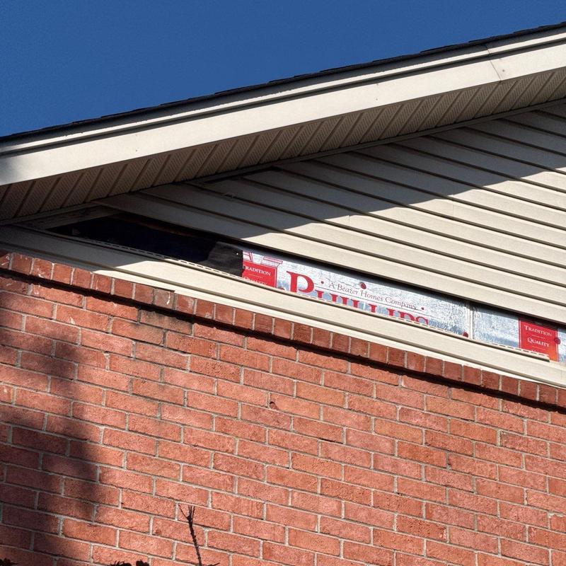 Soffit vent installation above brick exterior wall