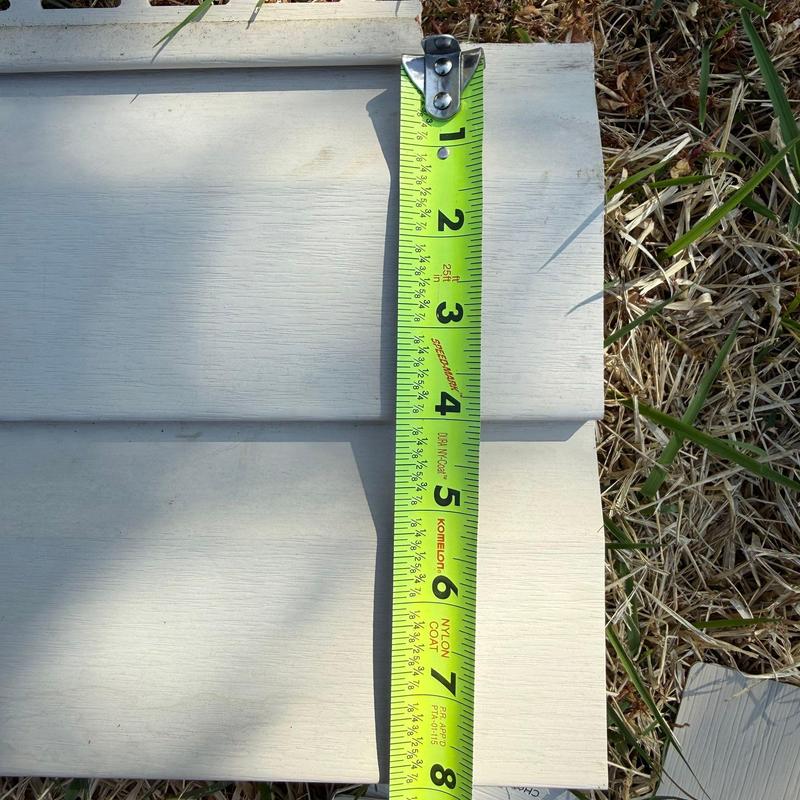 Vinyl siding panel measured with tape measure