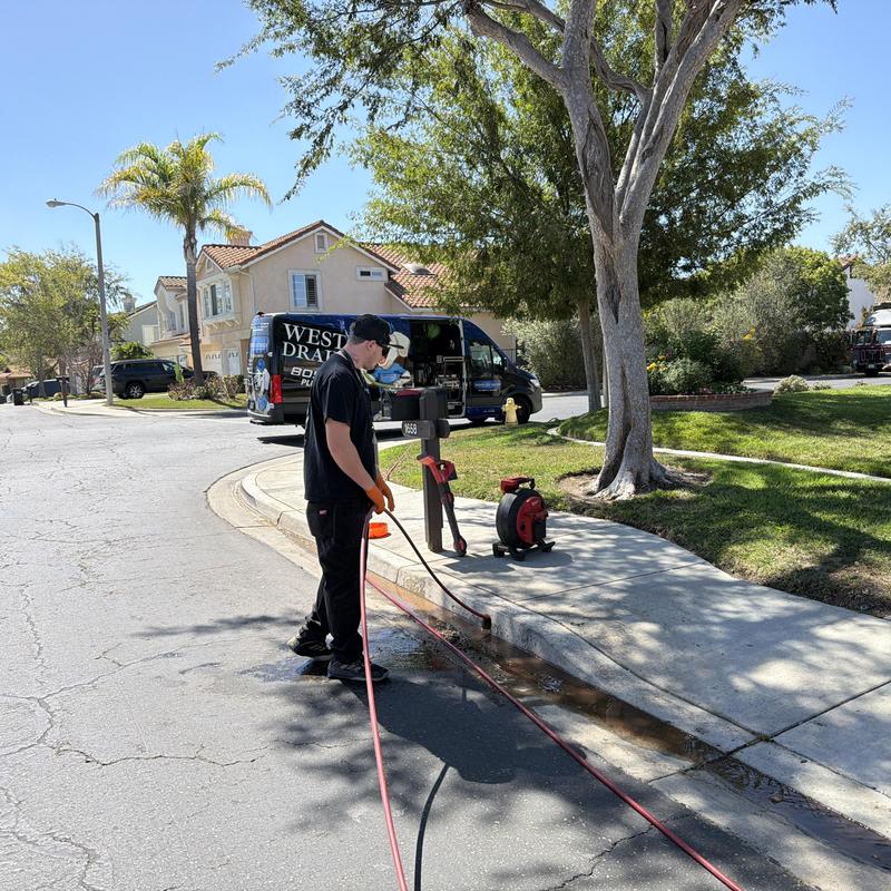 Storm drain hydro jetting on residential street curb Storm drain hydro jetting on residential street curb