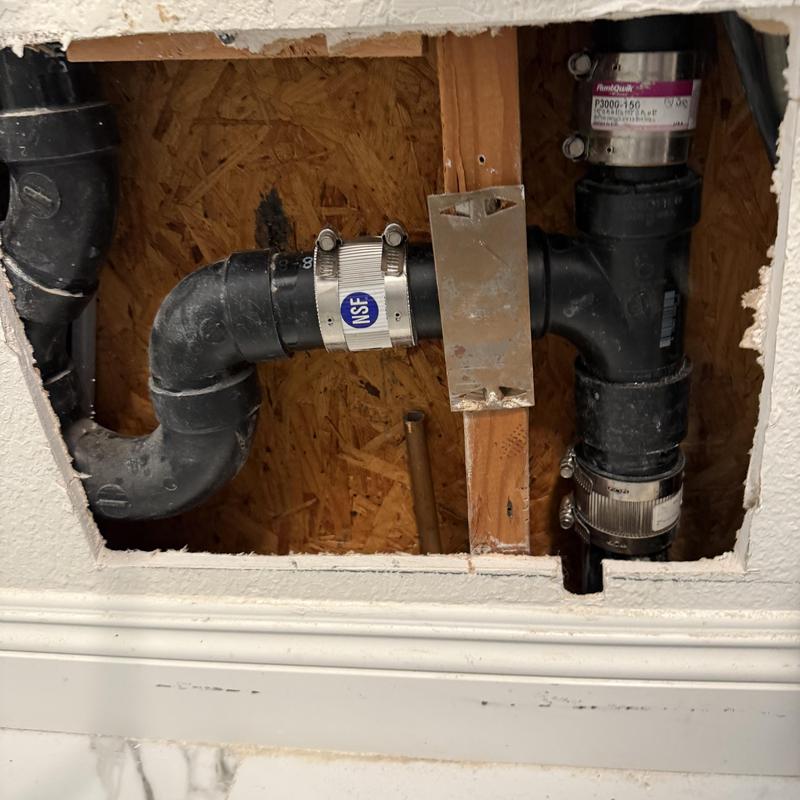 ABS drain pipe with metal clamps in wall cavity