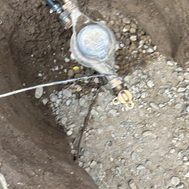 Water meter and pipe exposed in soil hole for repair Water meter and pipe exposed in soil hole for repair