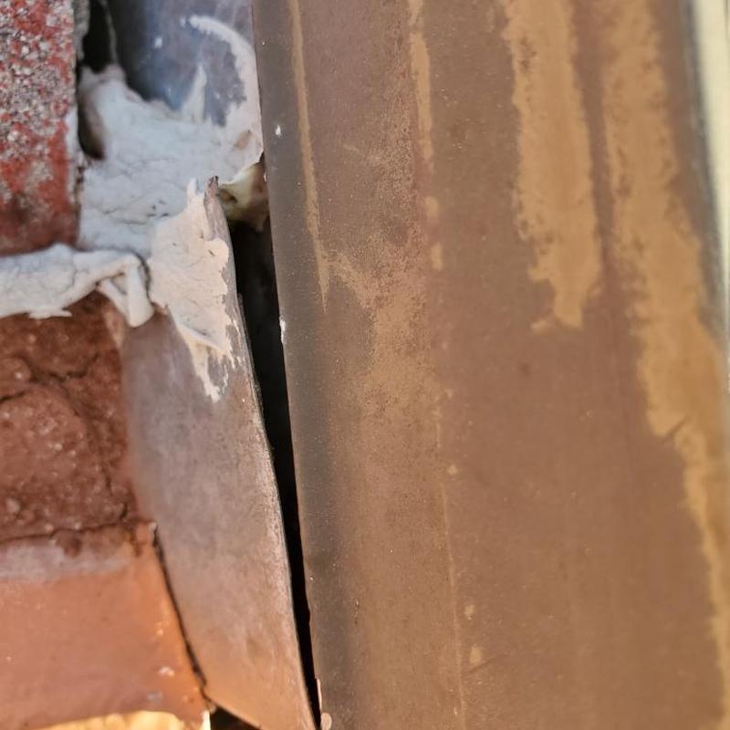 Tile roof flashing gap with sealant and rust spots