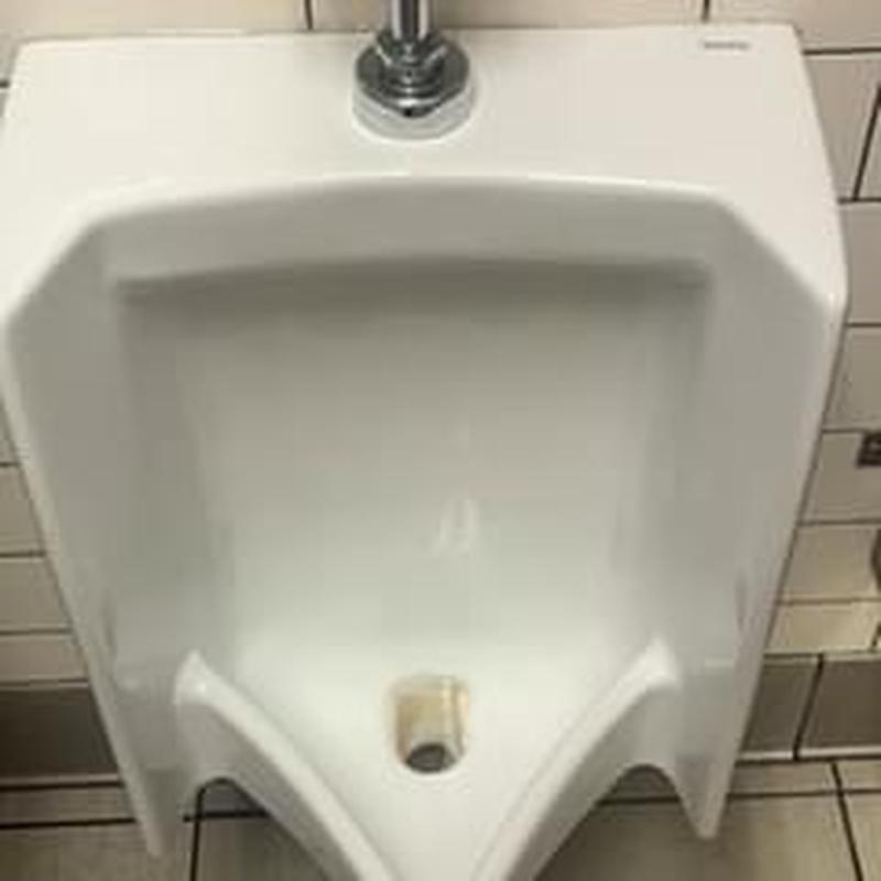 Urinal drain with flushing valve in tiled restroom Urinal drain with flushing valve in tiled restroom