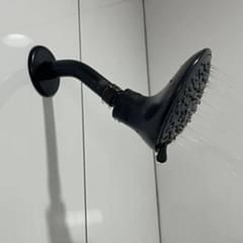 Shower head with water flow on white tile wall Shower head with water flow on white tile wall