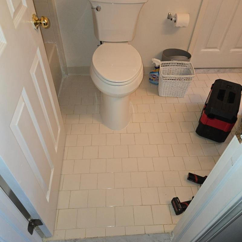Toilet installation in small bathroom with tools nearby