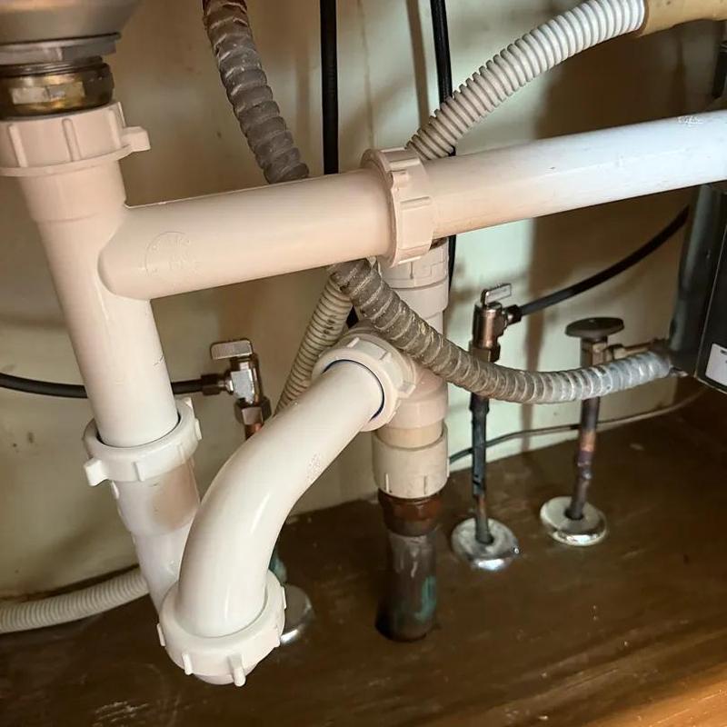 Kitchen sink PVC drain pipes and water shutoff valves under cabinet