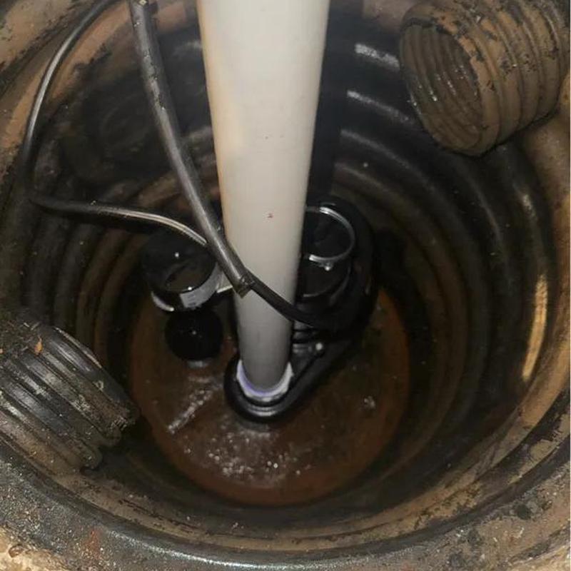 Sump pump basket inside a pit with piping and wiring