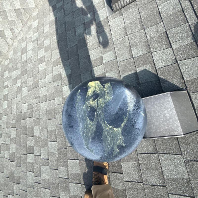 Metal vent cap with hail damage on shingled roof