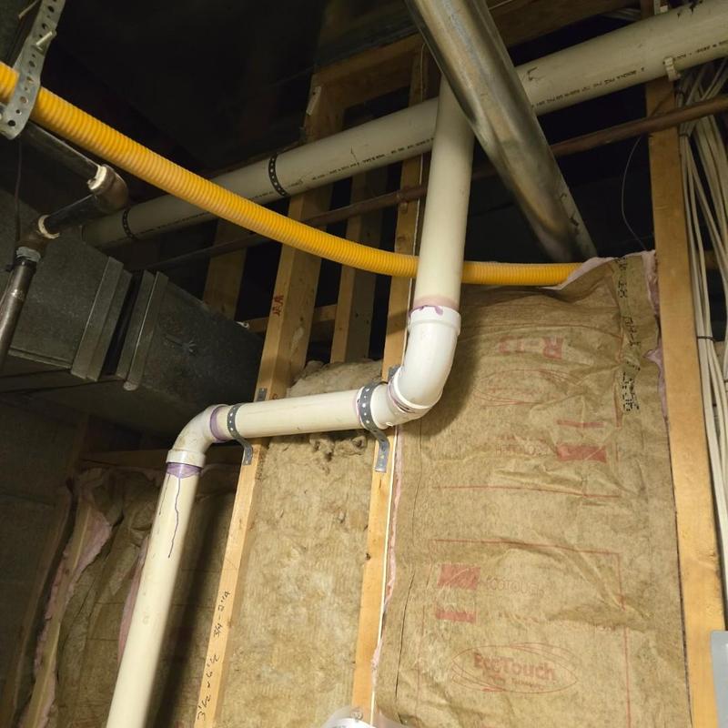 PVC drain pipe secured with metal brackets in wall cavity