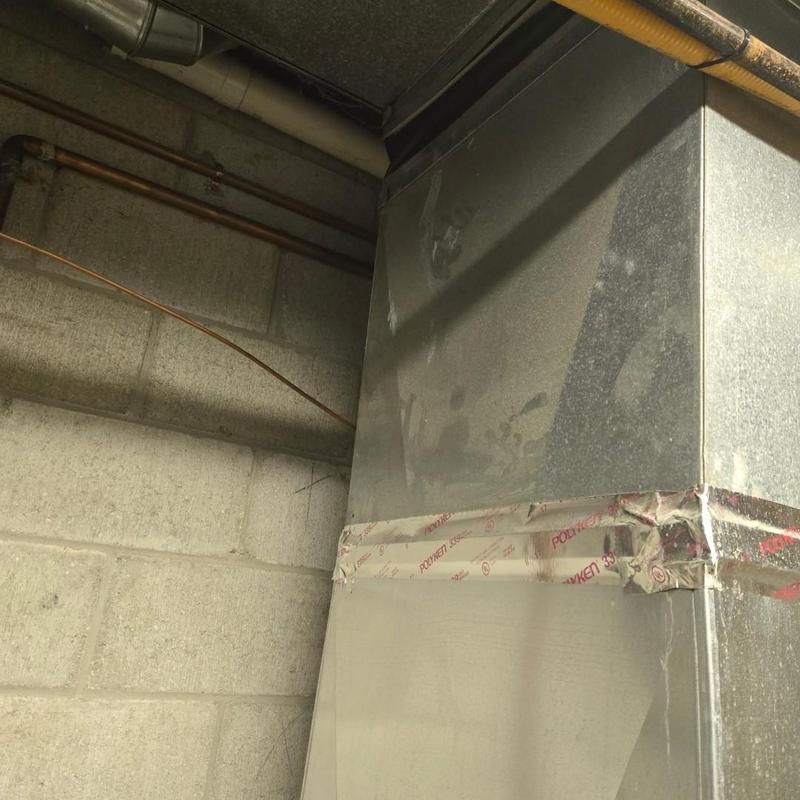 Metal ductwork with sealing tape in basement corner