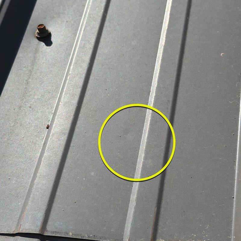 Metal roof panel with hail damage circled in yellow