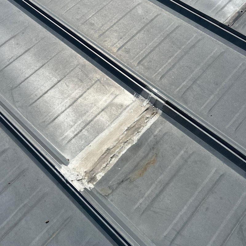 Metal roof panel with sealant patch and weathering