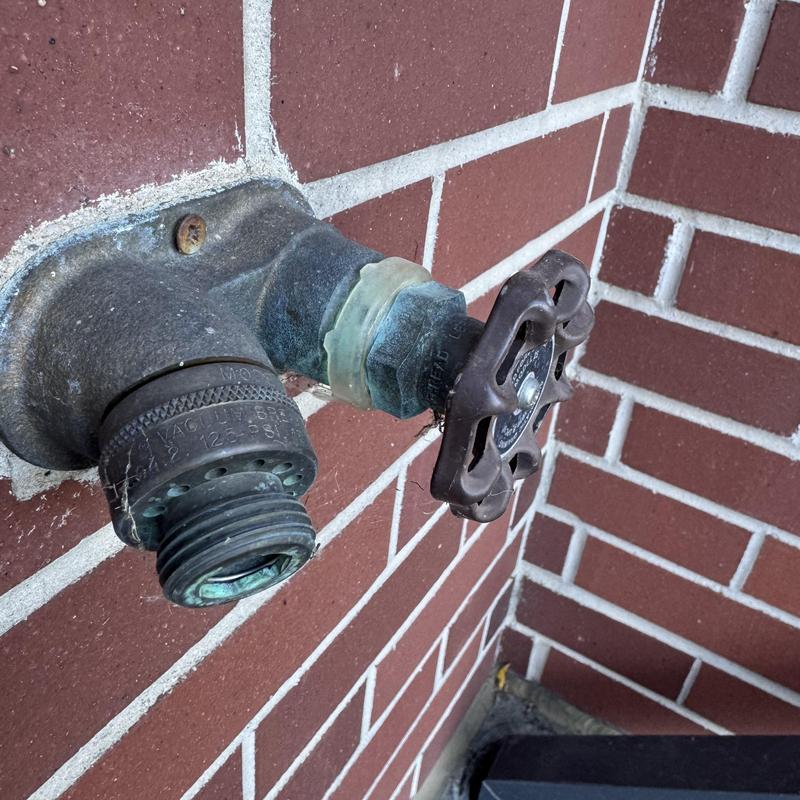 Outdoor hose bib valve with corroded fittings on brick wall Outdoor hose bib valve with corroded fittings on brick wall