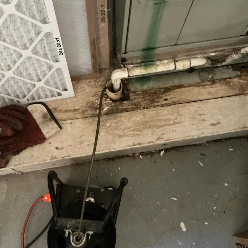 AC drain line with cleaning cable inserted near unit
