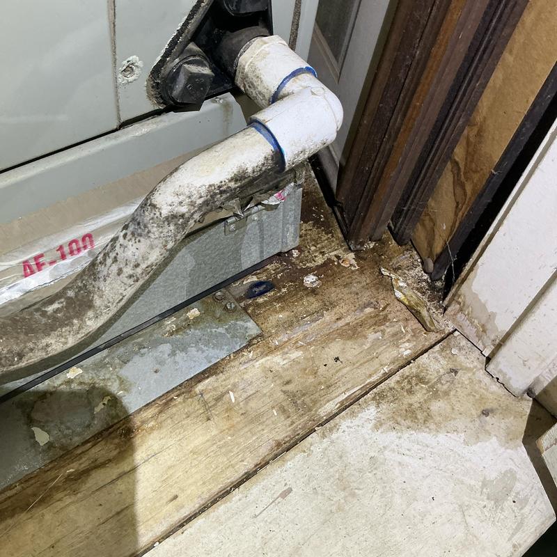 AC drain pipe with water damage on wood floor