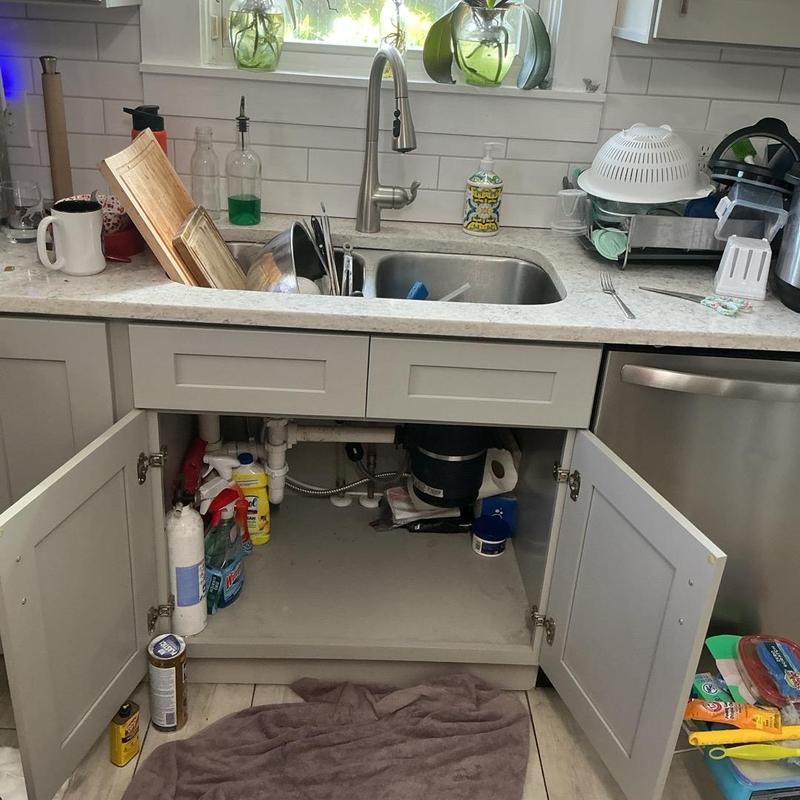 Kitchen sink faucet and drain pipe under cabinet open
