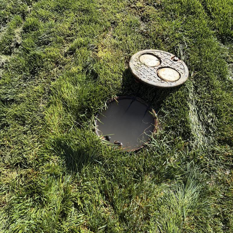 Watermain access hole with removed cover in grass Watermain access hole with removed cover in grass