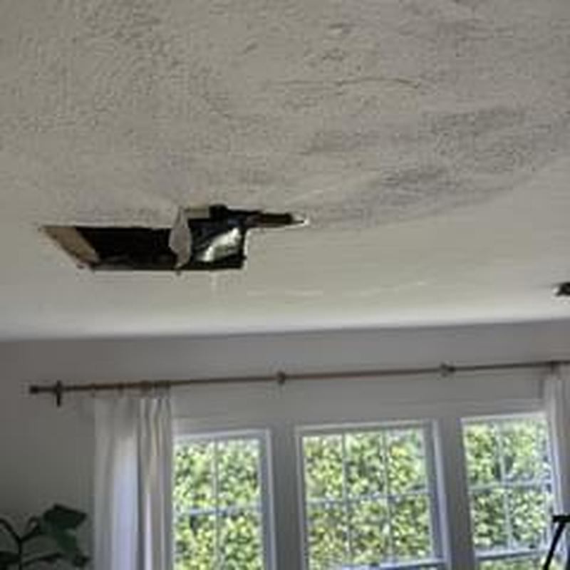 Ceiling with water damage hole above windows