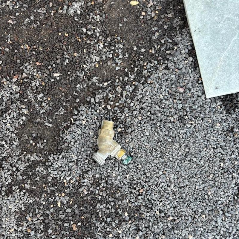 Hose bib valve on gravel backyard surface