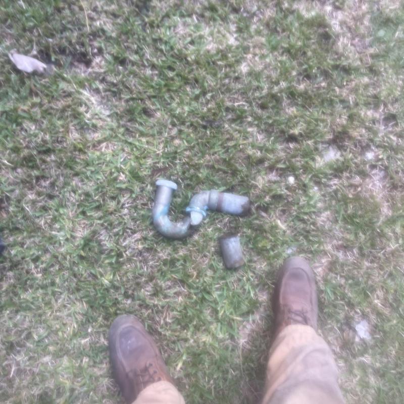 P-trap pipe sections on grass near work boots P-trap pipe sections on grass near work boots