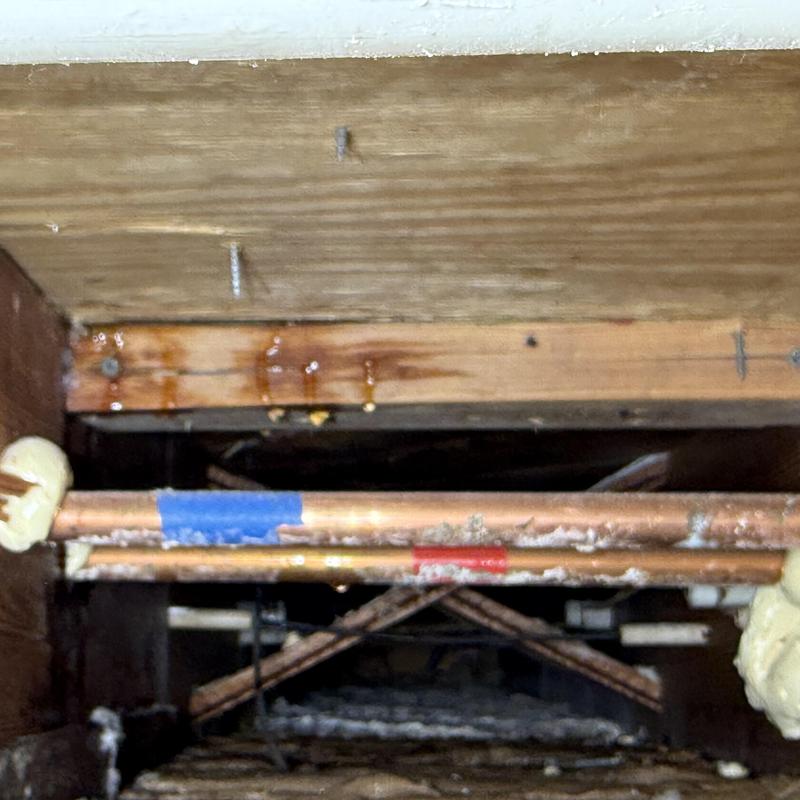Copper shower pipes with water leaks on wooden beam
