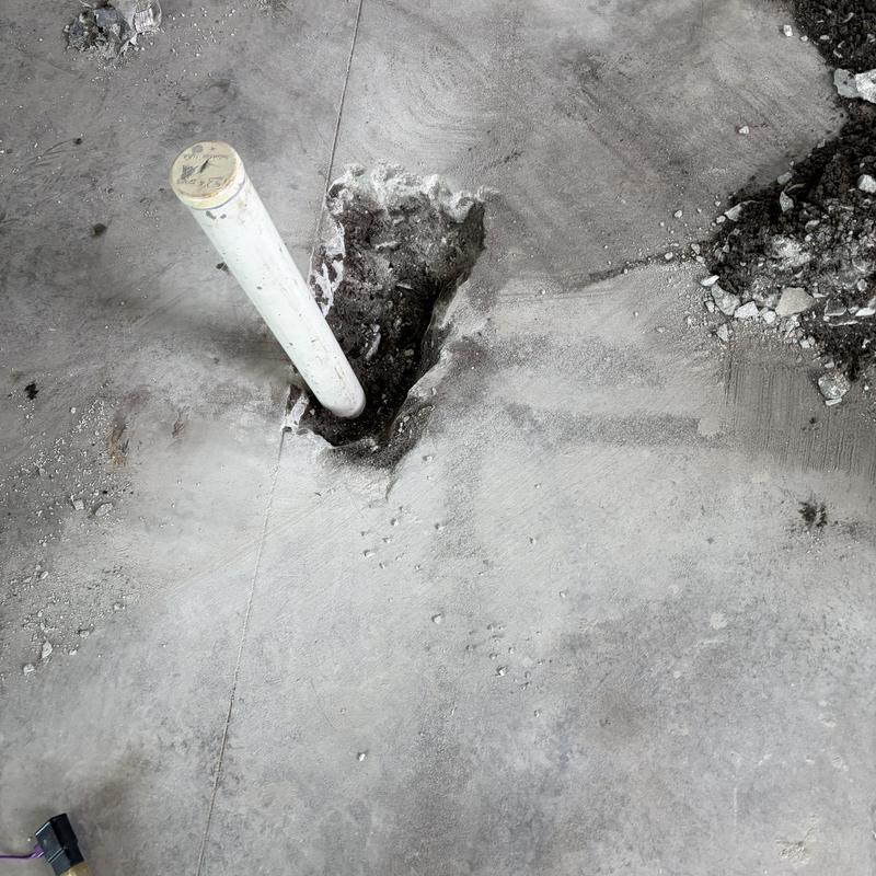 Bathroom sink drain pipe exposed in concrete floor