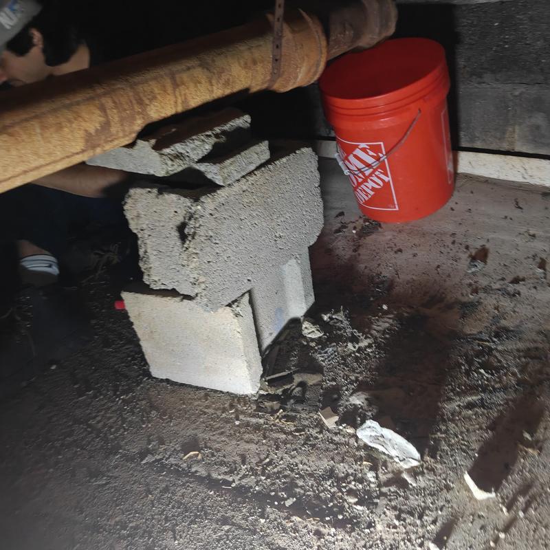 Rusty laundry drain pipe with concrete block support Rusty laundry drain pipe with concrete block support
