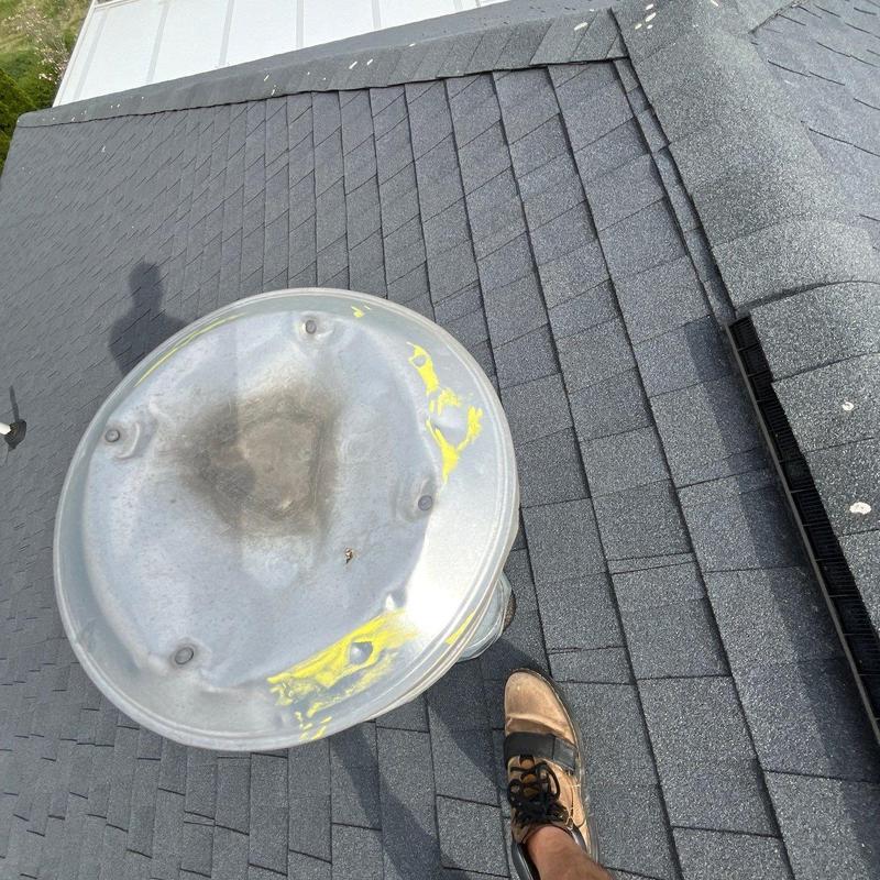 Metal vent cover with dents and yellow paint on shingles