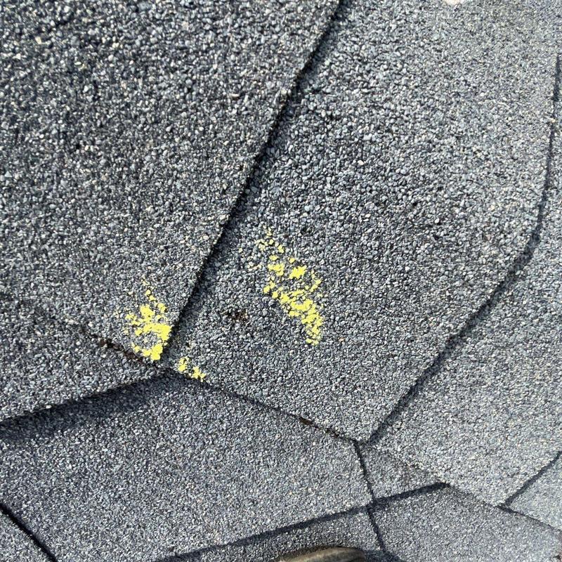 Asphalt shingles with hail damage marked in yellow
