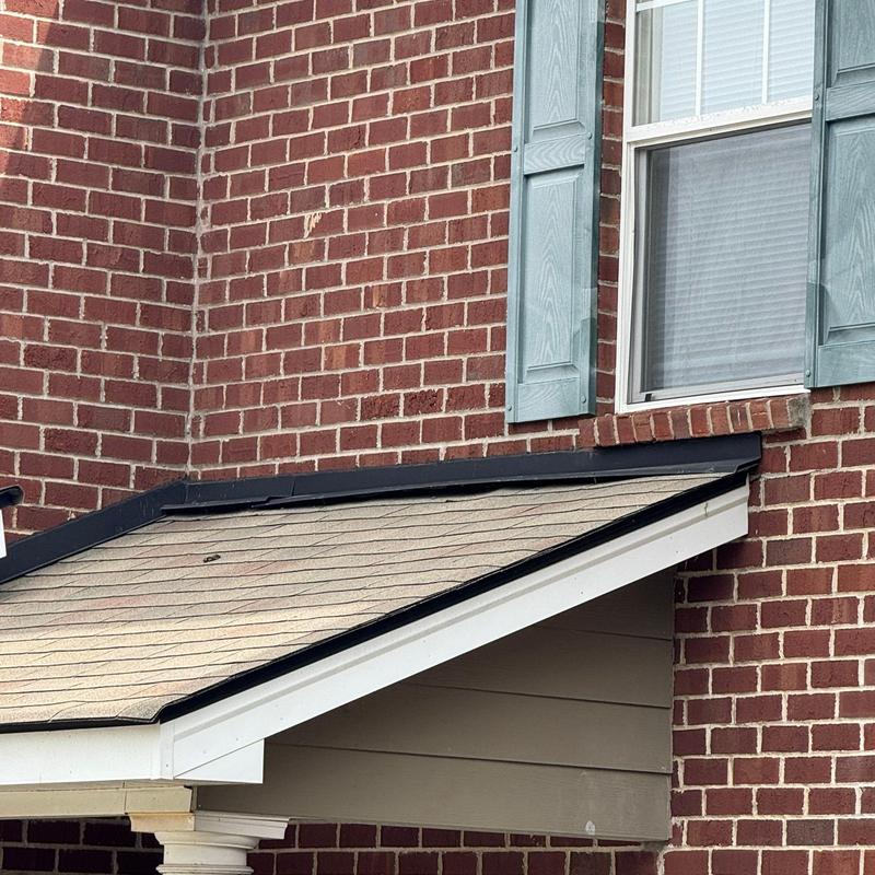 Roof shingles with visible hail damage near window trim