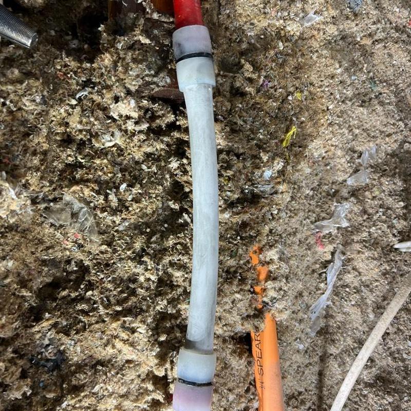 PEX pipe section with couplings installed in attic insulation background