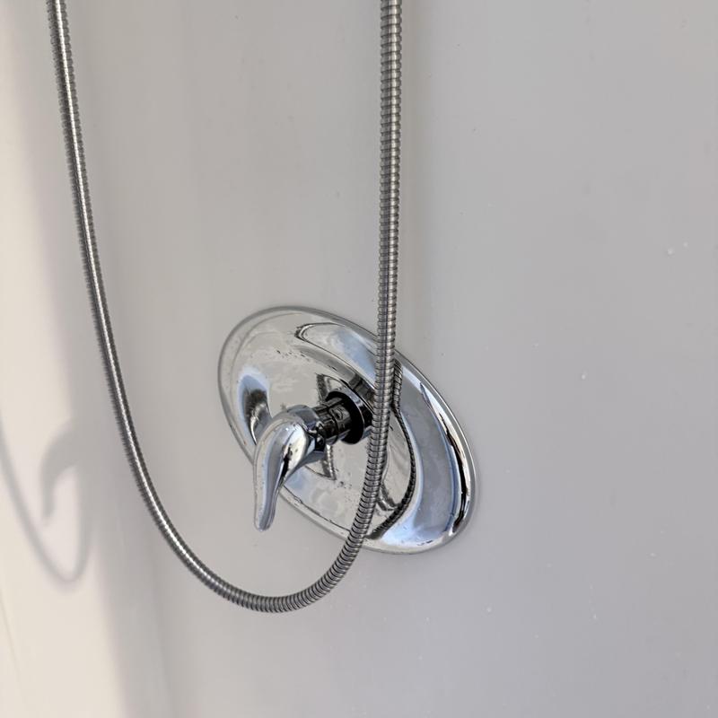 Shower valve with handheld hose in white tub wall Shower valve with handheld hose in white tub wall