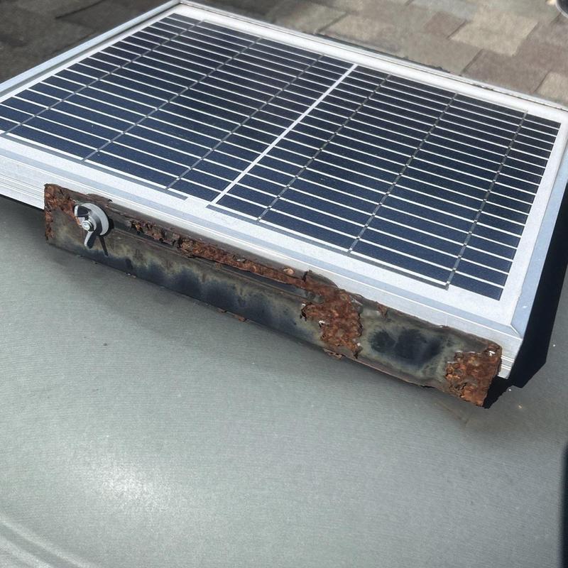 Solar panel with rusted mounting bracket on roof