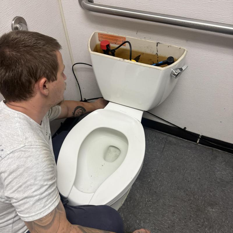 Toilet tank repair with technician in employee bathroom