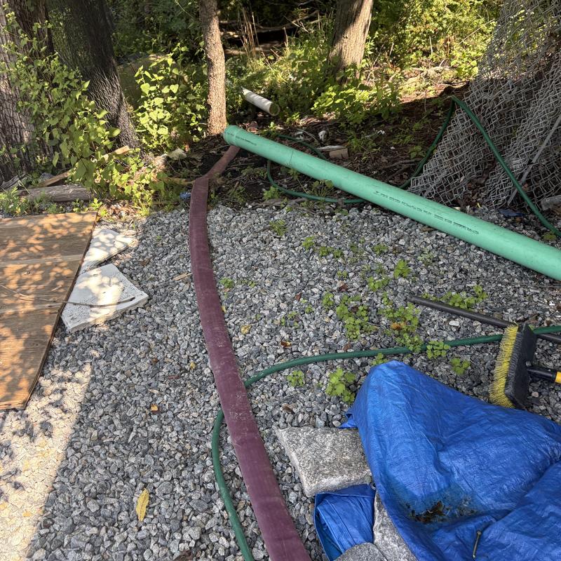 Sewer pipe and pump hose on gravel ground Sewer pipe and pump hose on gravel ground