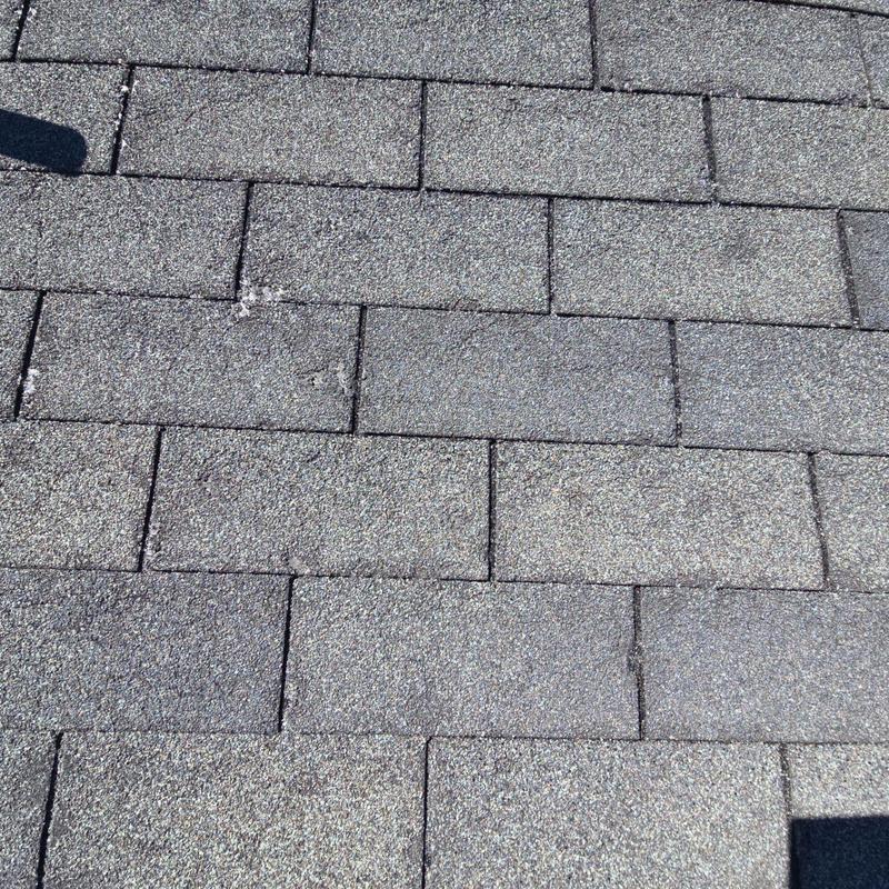 Asphalt roof shingles with visible surface damage Asphalt roof shingles with visible surface damage