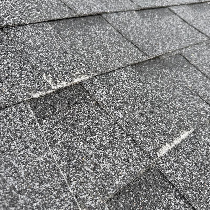Asphalt roof shingles with visible wear marks Asphalt roof shingles with visible wear marks