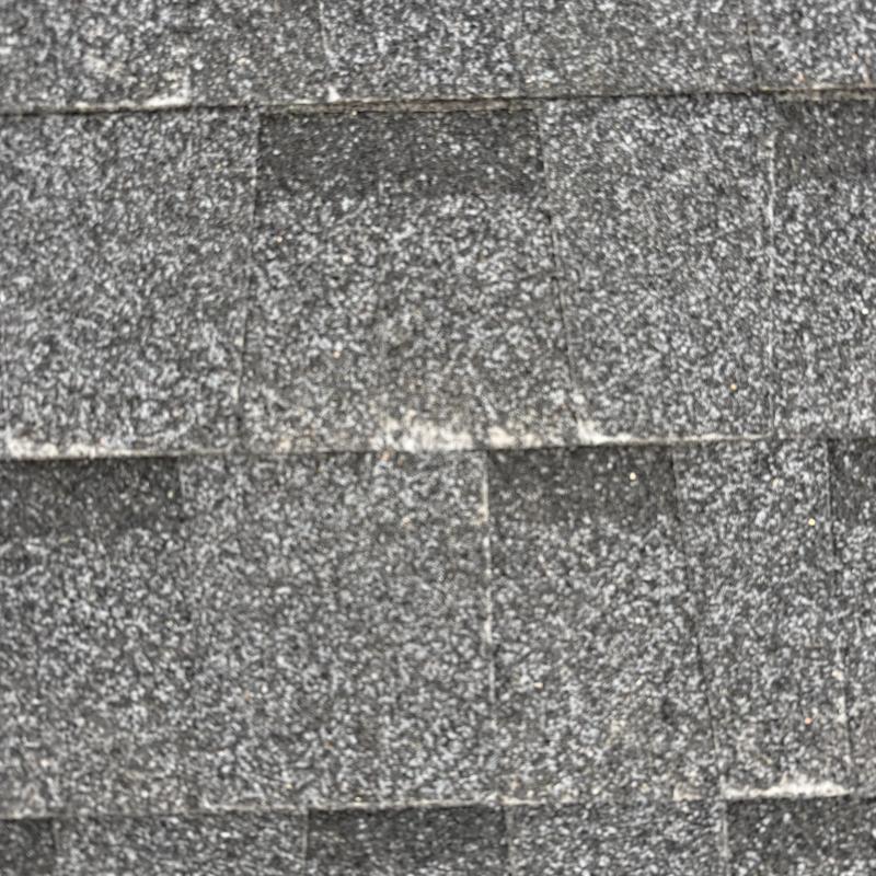 Asphalt roof shingles with visible granule wear Asphalt roof shingles with visible granule wear