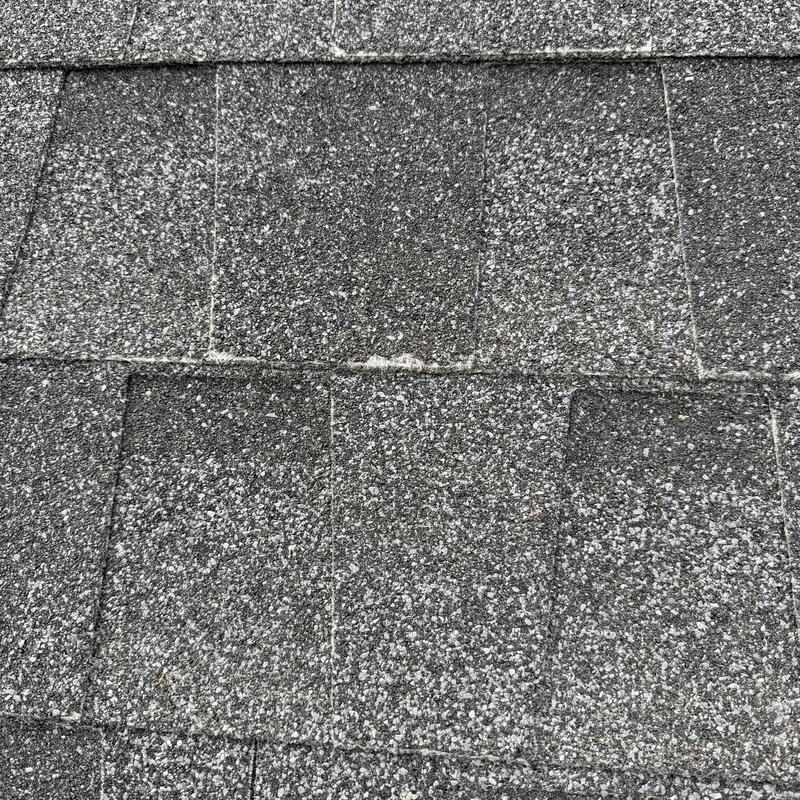 Asphalt roof shingles close-up with hail damage Asphalt roof shingles close-up with hail damage