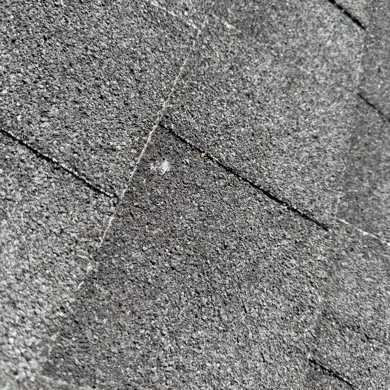 Asphalt roofing shingles with hail impact damage Asphalt roofing shingles with hail impact damage