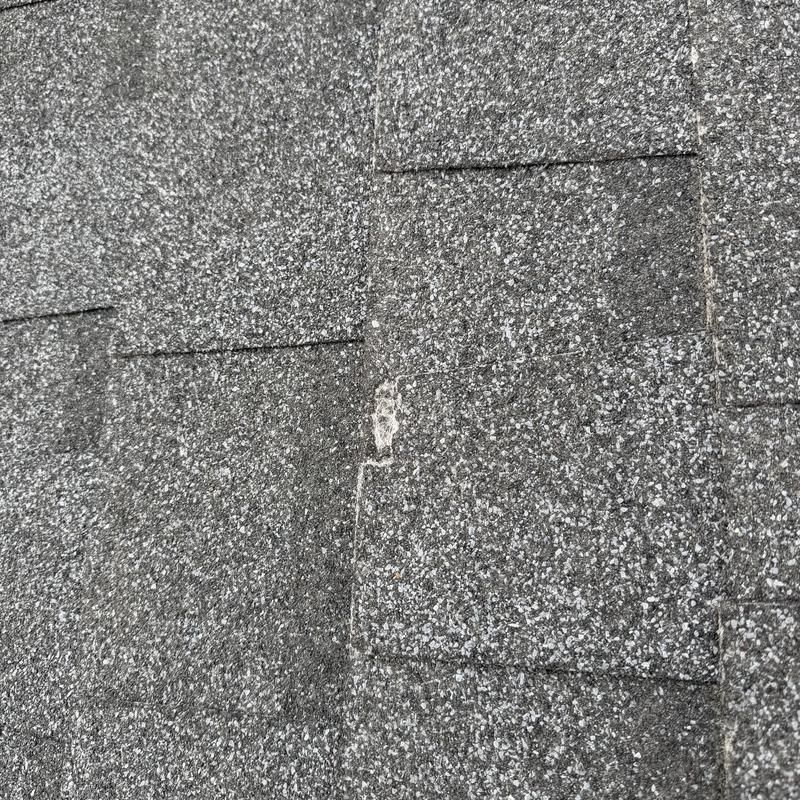 Asphalt shingle roof with hail damage spot Asphalt shingle roof with hail damage spot