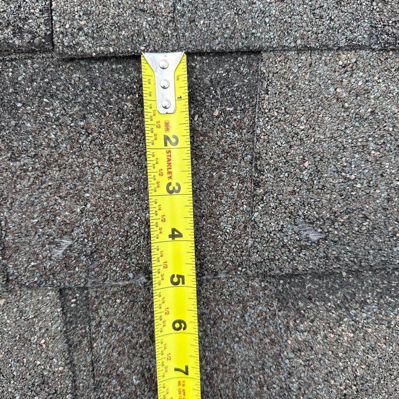 Asphalt shingles with measuring tape showing damage