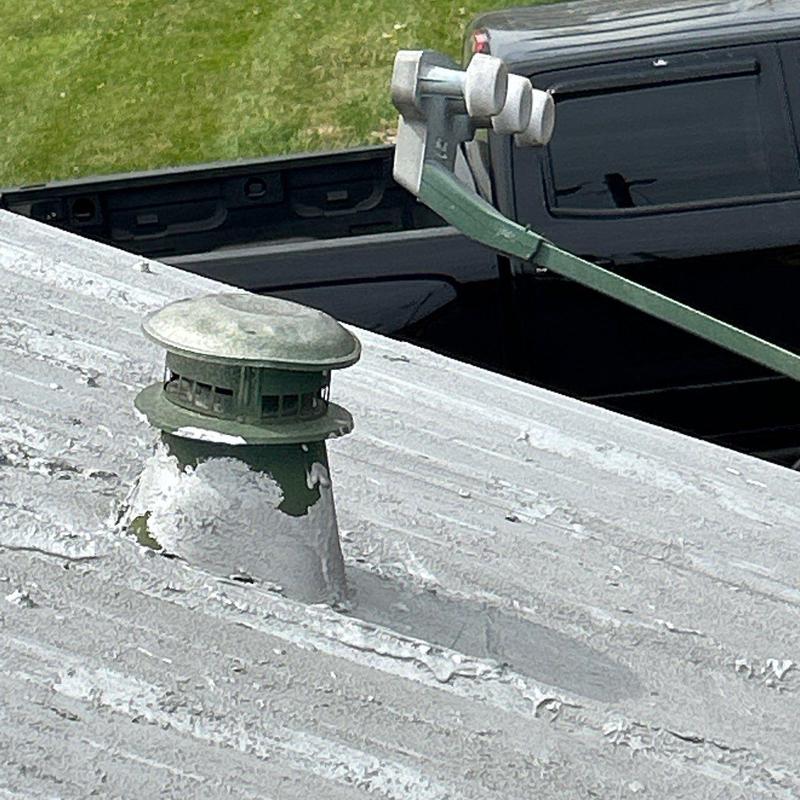 Metal roof vent with flaking paint and rust spots