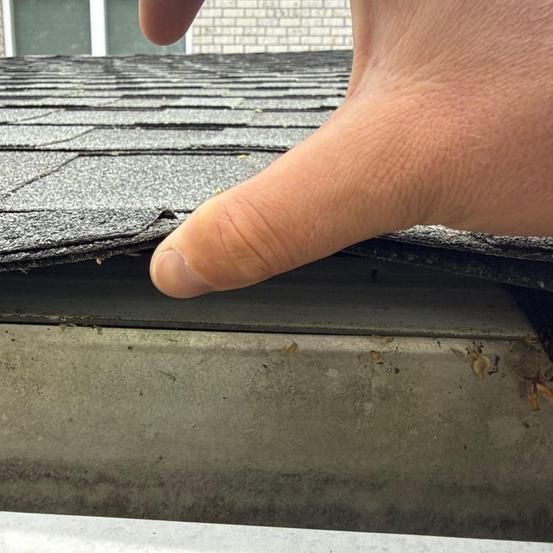 Asphalt shingles lifted showing roof edge damage