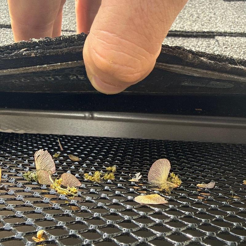 Roof shingle lifted to reveal debris on gutter guard mesh