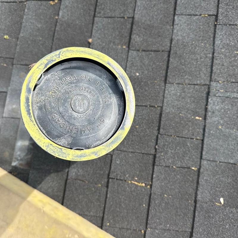 Roof plumbing vent cap with yellow sealant on shingles