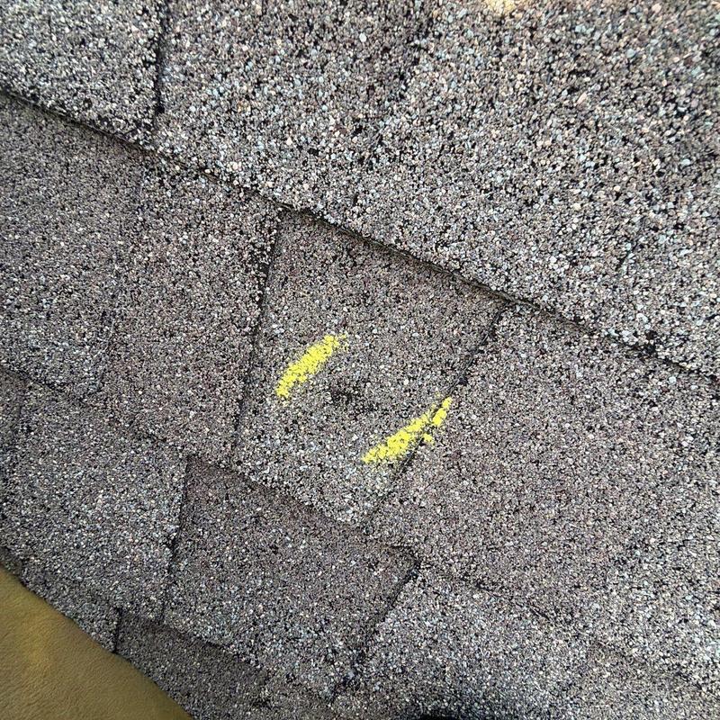 Asphalt shingles with hail damage marked in yellow